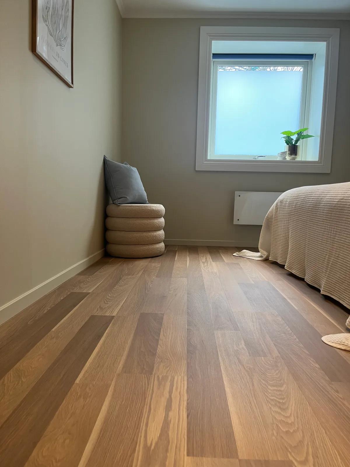 Nylagt eikeparkett i soverom med pouf og vindu – typisk resultat fra et Flip-prosjekt